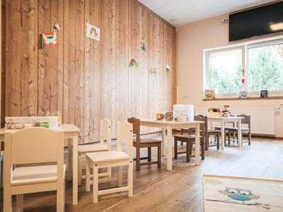 Bright room with children's chairs and tables in front of a wooden wall and window
