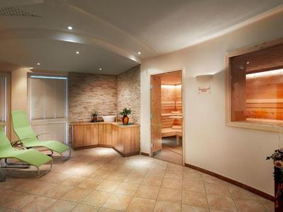 Gemütlicher Wellnessbereich mit grünen Liegestühlen und hölzerner Sauna.