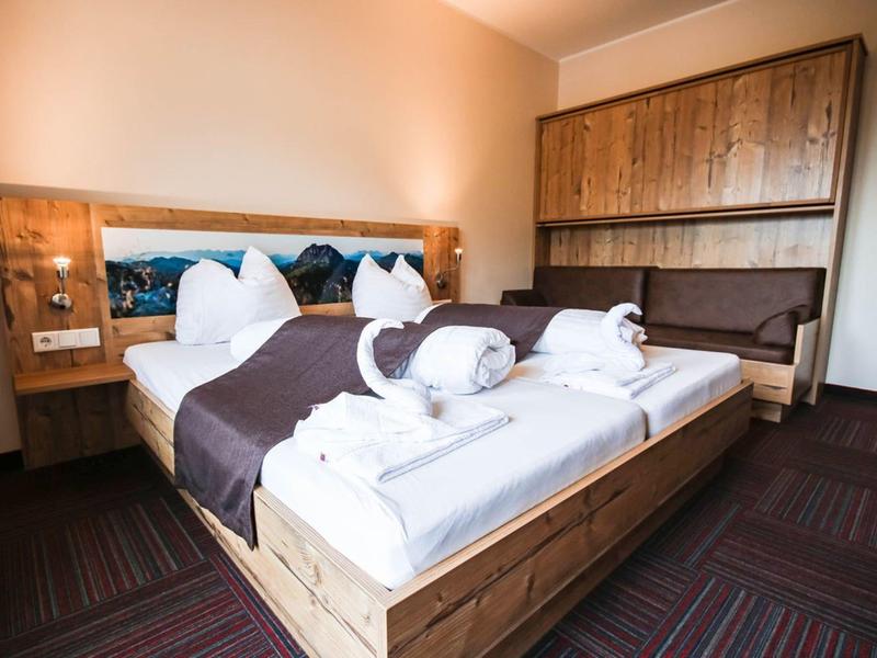 Gemütliches Schlafzimmer mit Holzbettrahmen, braunem Teppich und eingebauter Sitzbank.