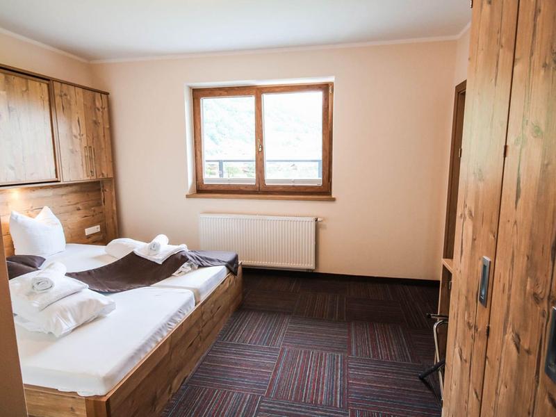 Gemütliches Schlafzimmer mit hölzernen Möbeln, Bett, Fenster und hellen Wänden.