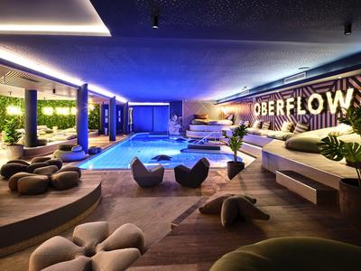 Nowoczesny kryty basen z meblami wypoczynkowymi i jasną atmosferą w hotelu.