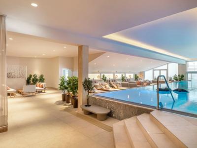 Piscina interna con ampie finestre e area relax in un hotel moderno.