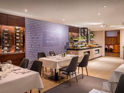 Modern restaurant met gedekte tafels en wijnrekken aan de muur.