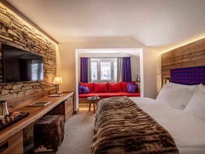 Camera d'albergo accogliente con letto grande, divano rosso e accenti in legno scuro