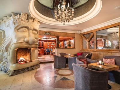 Accogliente area lounge dell'hotel con camino a forma di volto e mobili eleganti.