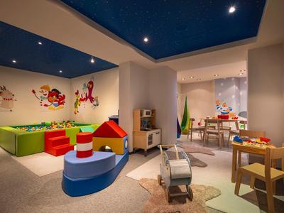Salle de jeux colorée pour enfants avec jouets, meubles et décorations murales.