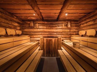 Sauna en bois chaleureux avec bancs larges et éclairage tamisé.