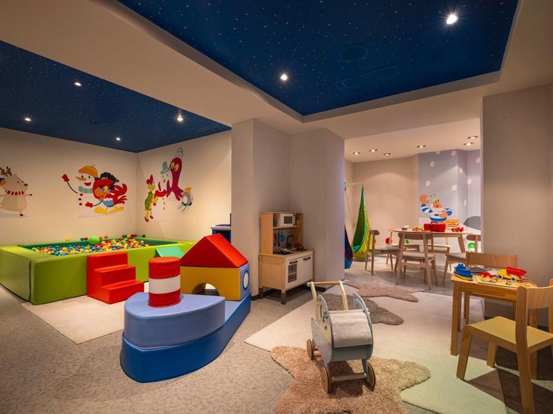 Salle de jeux colorée pour enfants avec jouets, meubles et décorations murales.