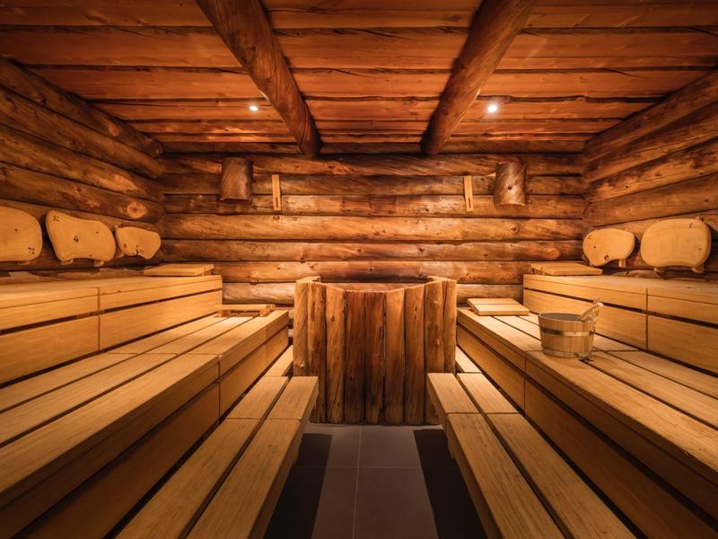 Sauna en bois chaleureux avec bancs larges et éclairage tamisé.