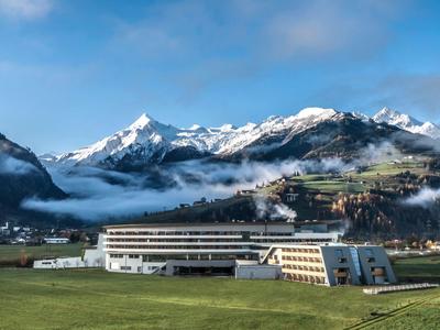 Edificio dell'hotel in paesaggio montuoso con cime innevate e nebbia.