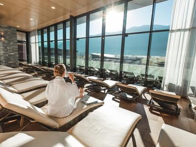 Donna in accappatoio si rilassa su una sdraio nell'area spa con vista panoramica sul mare.