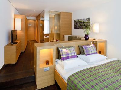 Camera d'hotel accogliente con letto matrimoniale, mobili in legno e illuminazione moderna.