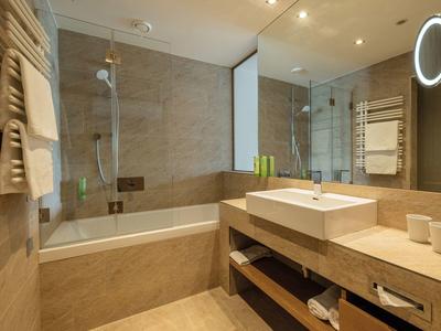 Bagno moderno con vasca da bagno, grande specchio e lavabo su piano in legno.