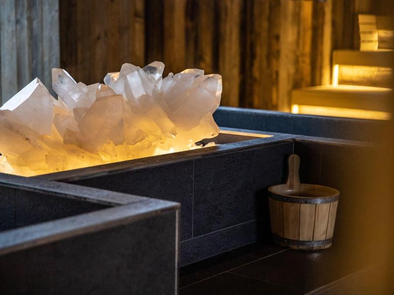 Grandi pietre di cristallo con luce calda in un ambiente tranquillo della spa accanto a un secchio di legno.