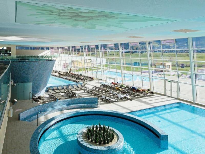 Piscina coperta luminosa con ampie finestre e vista sulle montagne in un hotel.