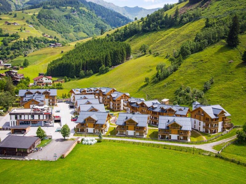 Resort di montagna con chalet in paesaggio verde e colline sullo sfondo