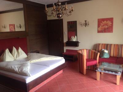 Chambre d'hôtel avec lit double, canapé rayé, table en verre et lustre.