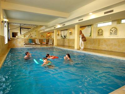 Vnitřní bazén s několika lidmi plavoucími a hrajícími si ve vodě.