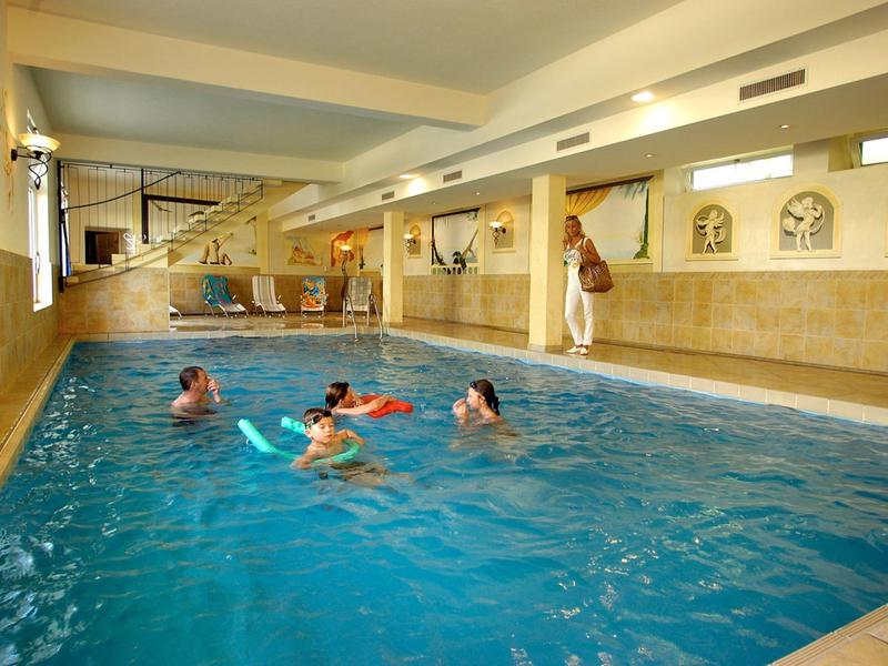 Vnitřní bazén s několika lidmi plavoucími a hrajícími si ve vodě.