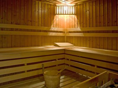 Wooden sauna interior with benches, bucket, and soft lighting creating a warm atmosphere.