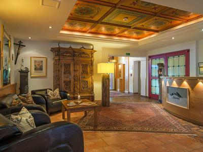 Przytulna lobby hotelowa z skórzanymi sofami, antycznymi meblami drewnianymi i dekoracyjnym sufitem.