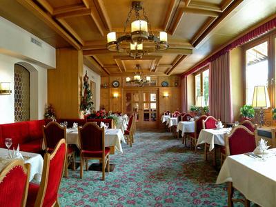 Ristorante elegante con tavoli apparecchiati, sedie rosse e soffitto in legno.
