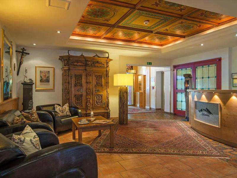 Acogedora zona de vestíbulo de hotel con sofás de cuero, armario de madera decorativo y luz cálida.