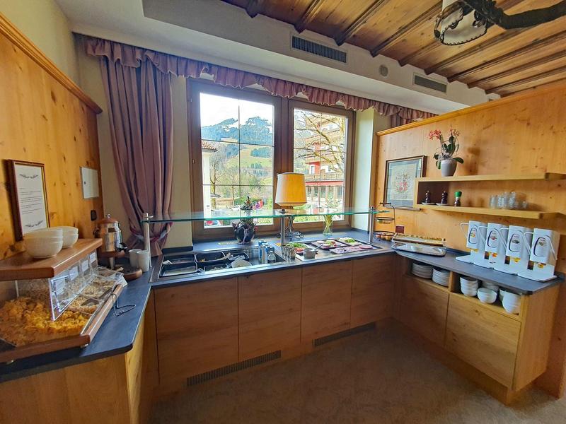Cocina moderna de hotel con gabinetes de madera, ventana grande y hermosa vista a las montañas.