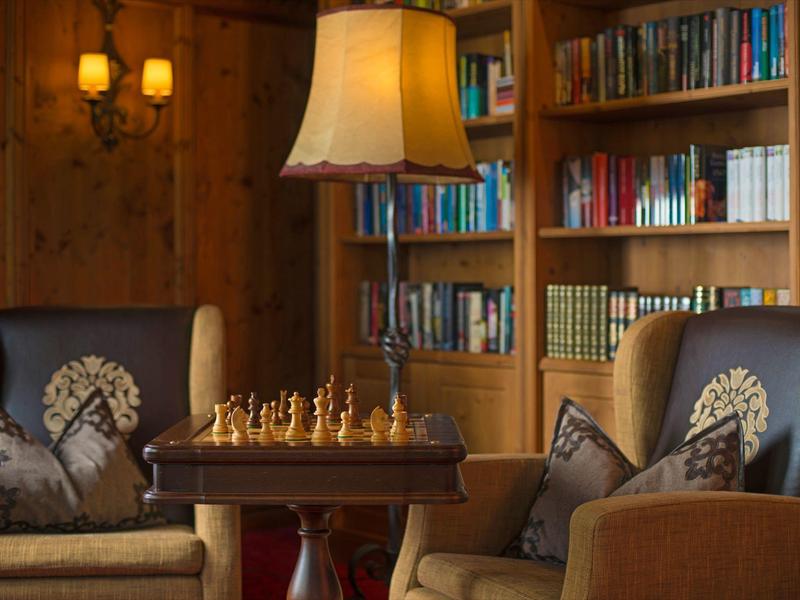 Sala acogedora con estanterías llenas de libros, dos sillones y una mesa con ajedrez