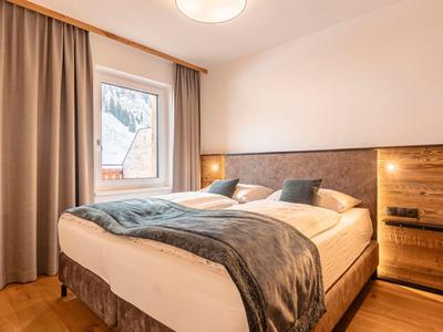 Przytulny pokój hotelowy z dużym łóżkiem podwójnym, drewnianą podłogą i oknem z zasłonami.