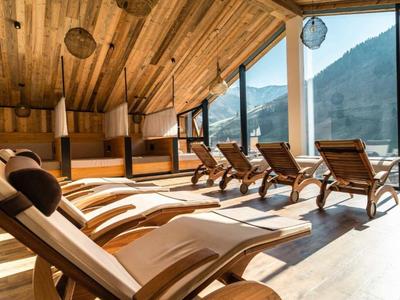 Ruhiger Entspannungsraum mit Holzliegen und Panoramablick auf Berge durch große Fenster.