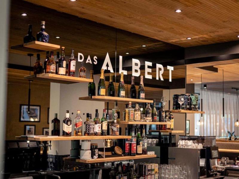 Bar z drewnianymi meblami i oświetleniem z nazwą "Das Albert".