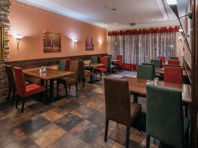 Příjemná jídelna s stolky a vícebarevnými židlemi v teplém osvětlení.