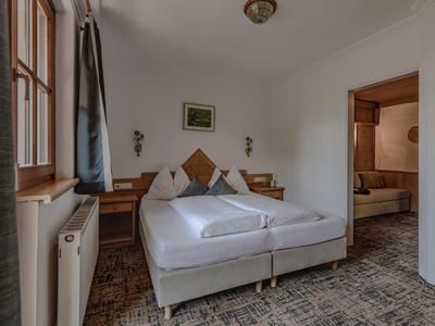 Příjemný dvoulůžkový pokoj s bílými stěnami, kobercem a dřevěným nábytkem v hotelu.