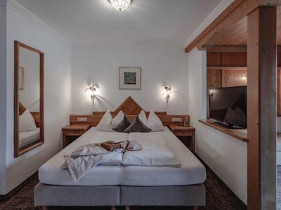 Pohodlný hotelový pokoj s manželskou postelí, nočními stolky a velkým nástěnným zrcadlem.