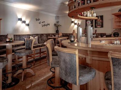 Accogliente bar dell'hotel con sedie in legno scuro e illuminazione calda.