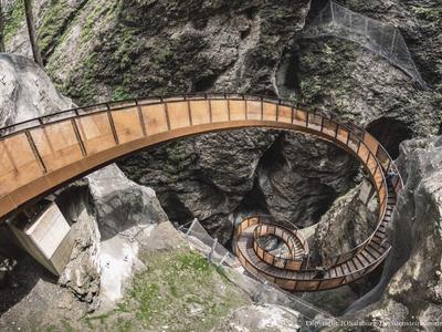 Úzká, klikatá dřevěná lávka prochází skalnatým, zalesněným údolím.