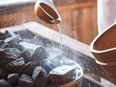 Voda je nalévána na horké kameny ve finské sauně k vytvoření páry.