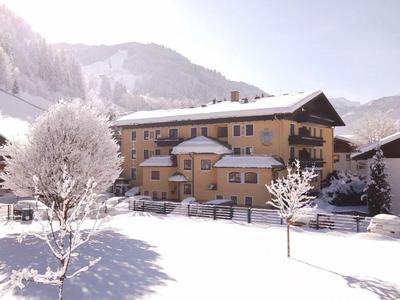 Budova hotelu v zasněžené zimní krajině s horami v pozadí.