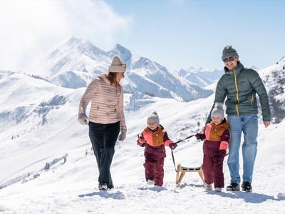 Rodina se dvěma dětmi a psem prochází zasněženými horami