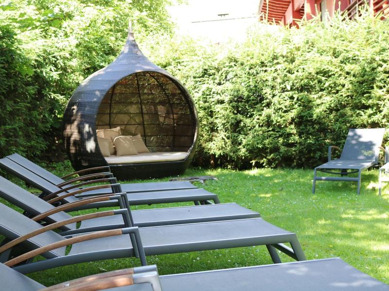 Několik lehátek na trávě s kulatou závěsnou židlí na zahradě.