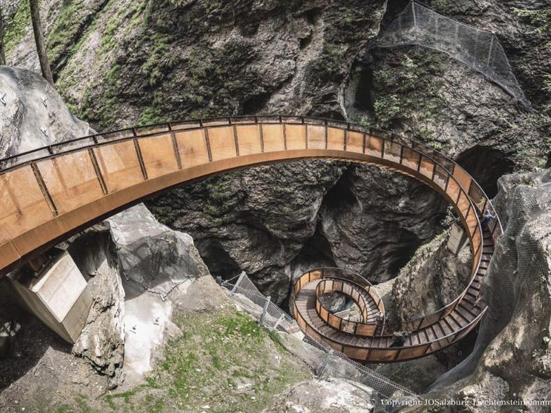 Úzká, klikatá dřevěná lávka prochází skalnatým, zalesněným údolím.