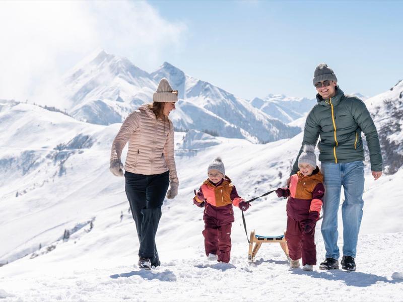 Rodina se dvěma dětmi a psem prochází zasněženými horami