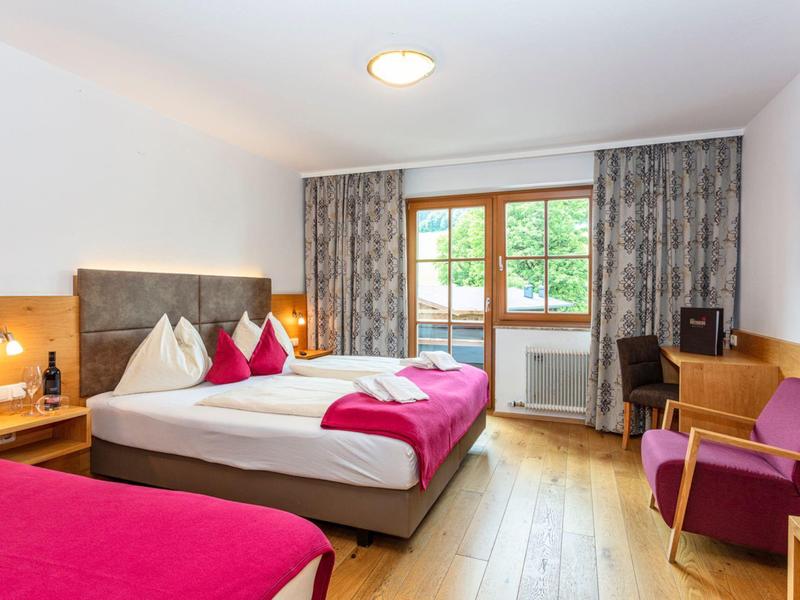 Pohodlný hotelový pokoj s manželskou postelí, balkonem a moderním nábytkem.