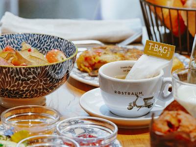 Tavolo apparecchiato con colazione con tè, pasticcini e ingredienti freschi.