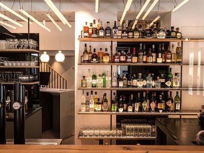 Area bar con scaffali illuminati pieni di bottiglie di liquore in un hotel moderno.