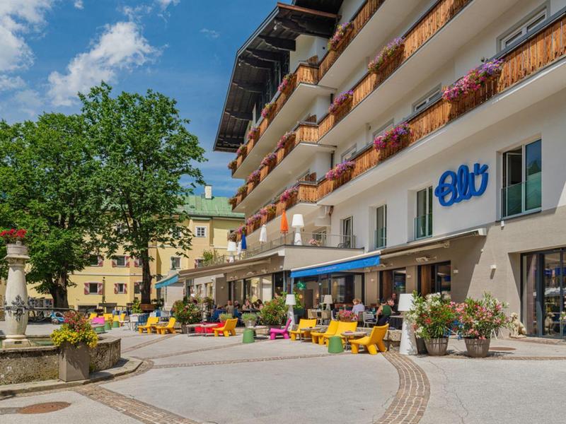 Hotel con balconi, area salotto e fontana sotto un cielo soleggiato