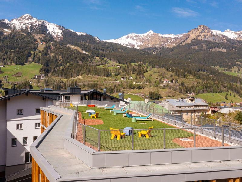 Terrazza sul tetto con campo da mini golf colorato davanti alle montagne alpine e cielo blu.