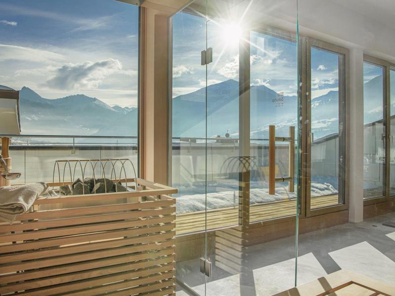 Veranda moderna con facciata in vetro e vista sulle montagne innevate al sole.