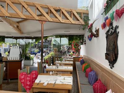 Pohodlná restaurace s dřevěnými stoly a barevnými polštáři na zdí